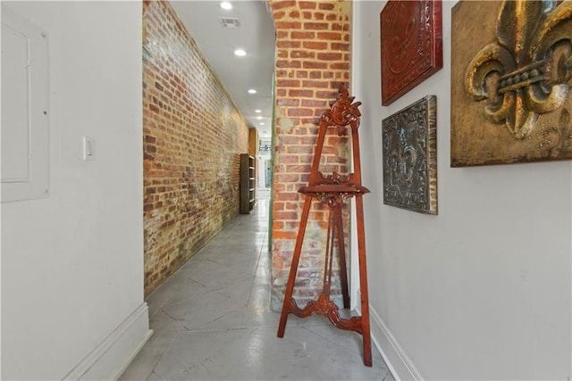 hall with tile flooring and brick wall