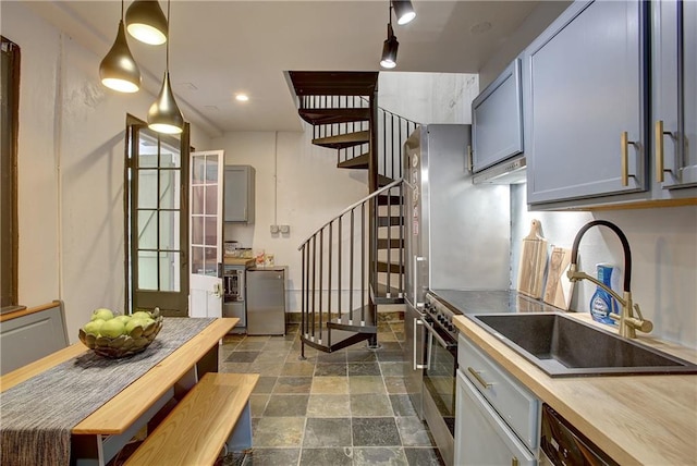 kitchen with decorative light fixtures, sink, dark tile flooring, and dishwasher