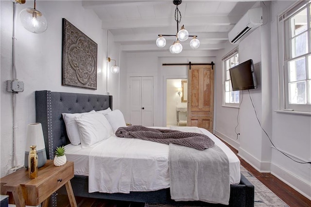 bedroom with dark hardwood / wood-style floors, a wall mounted AC, beamed ceiling, a barn door, and a chandelier