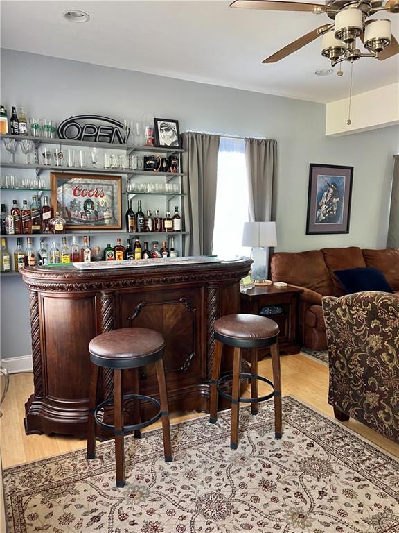 bar featuring light wood-type flooring and ceiling fan