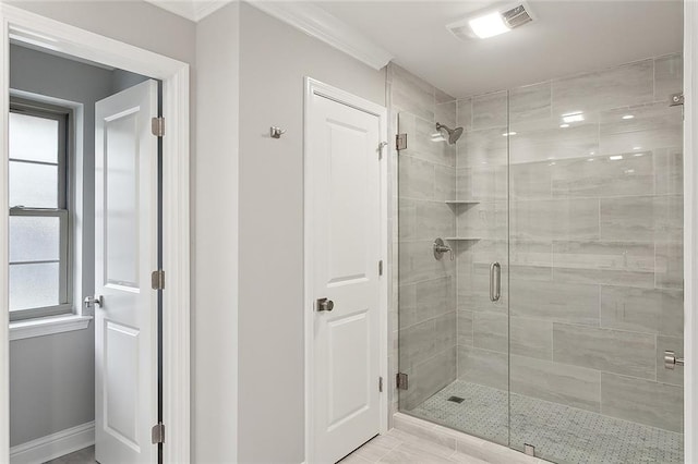 bathroom with a shower with shower door and ornamental molding