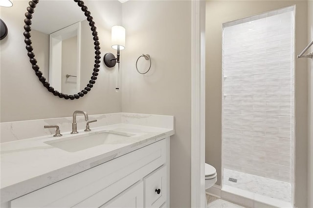 bathroom featuring toilet, a tile shower, and vanity