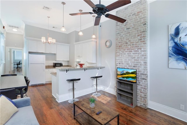 living room featuring ceiling fan with notable chandelier, dark hardwood / wood-style flooring, crown molding, and brick wall