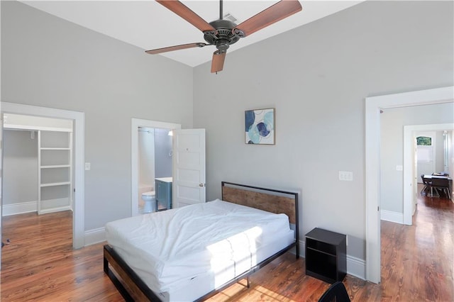 bedroom with ceiling fan, hardwood / wood-style flooring, high vaulted ceiling, ensuite bath, and a spacious closet