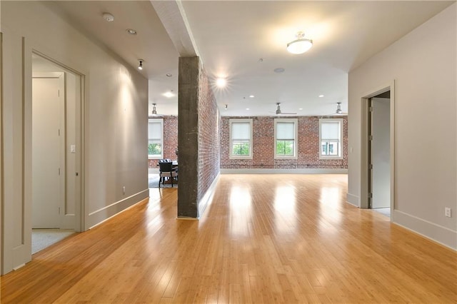 foyer featuring light hardwood / wood-style floors, brick wall, and ceiling fan