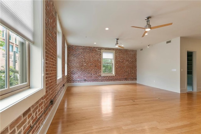 spare room featuring brick wall, ceiling fan, and light hardwood / wood-style floors