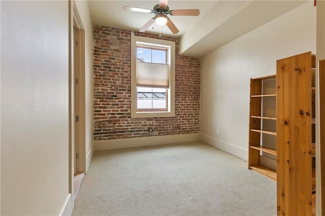 spare room featuring brick wall, carpet floors, and ceiling fan