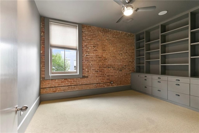 empty room with ceiling fan, light colored carpet, and brick wall