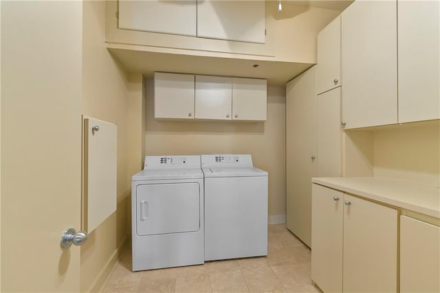 laundry area featuring cabinets, light tile floors, and washing machine and clothes dryer