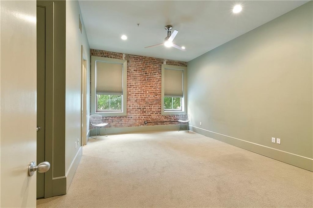 carpeted empty room with brick wall, ceiling fan, and a healthy amount of sunlight