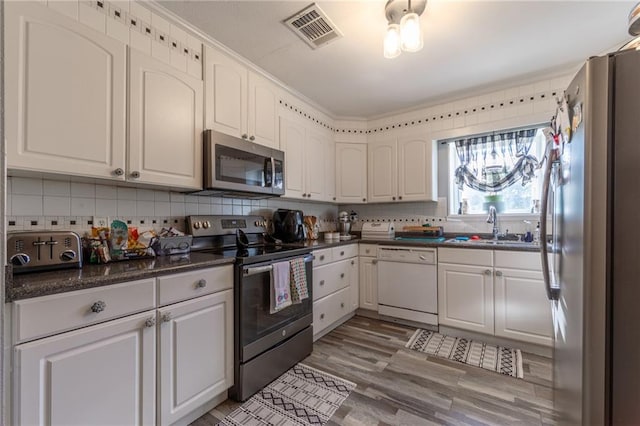 kitchen with light hardwood / wood-style flooring, tasteful backsplash, white cabinets, sink, and appliances with stainless steel finishes