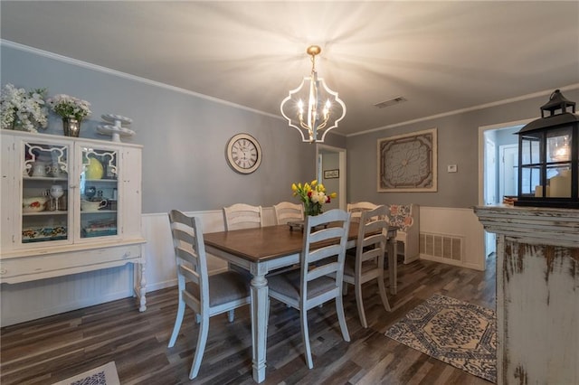 dining room with a notable chandelier, ornamental molding, and dark wood-type flooring