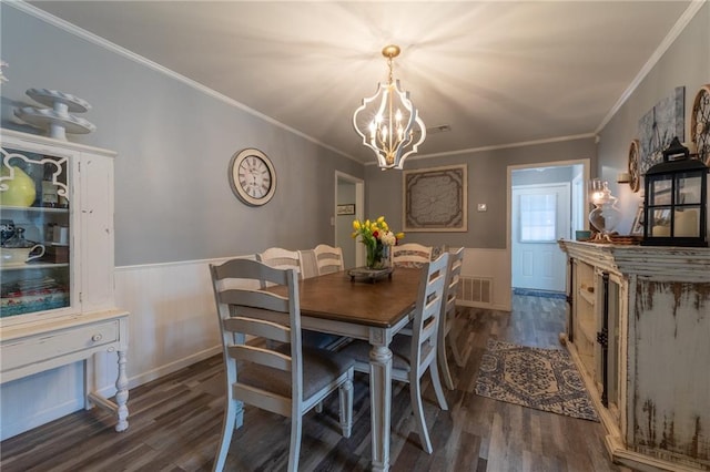 dining space with dark hardwood / wood-style floors, ornamental molding, and a chandelier