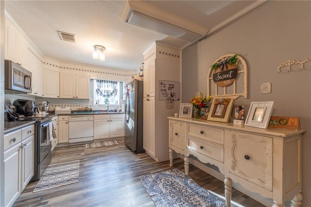 kitchen with crown molding, dark wood-type flooring, stainless steel appliances, sink, and tasteful backsplash