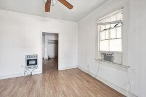 unfurnished room with hardwood / wood-style floors, cooling unit, a healthy amount of sunlight, and heating unit