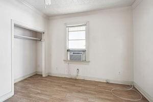 unfurnished bedroom featuring cooling unit, light hardwood / wood-style floors, and a closet