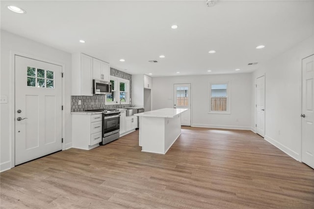 kitchen featuring a center island, light hardwood / wood-style flooring, white cabinets, and appliances with stainless steel finishes