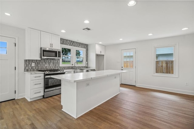 kitchen featuring a wealth of natural light, stainless steel appliances, hardwood / wood-style flooring, and white cabinetry