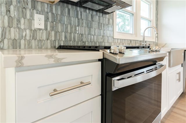 kitchen with light hardwood / wood-style floors, white cabinets, and light stone countertops