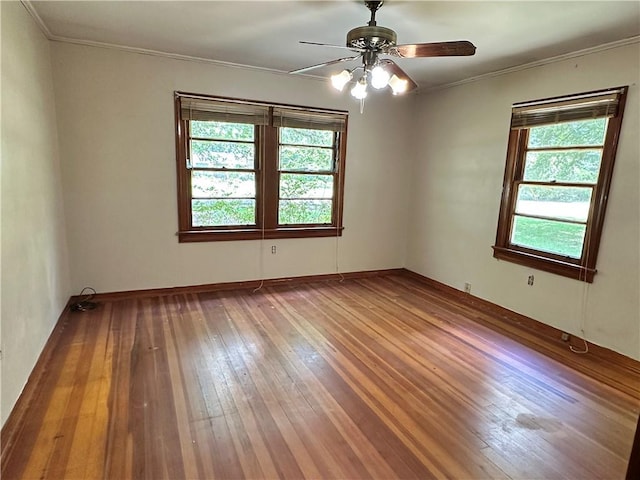 empty room with a wealth of natural light, ceiling fan, ornamental molding, and hardwood / wood-style flooring