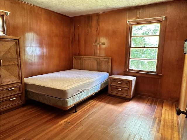 bedroom featuring wooden walls, a textured ceiling, and hardwood / wood-style flooring