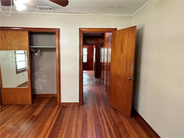 unfurnished bedroom with a closet, dark hardwood / wood-style floors, and multiple windows