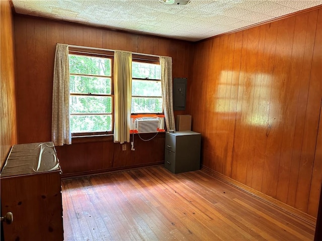 unfurnished room featuring a wealth of natural light, dark wood-type flooring, and wood walls