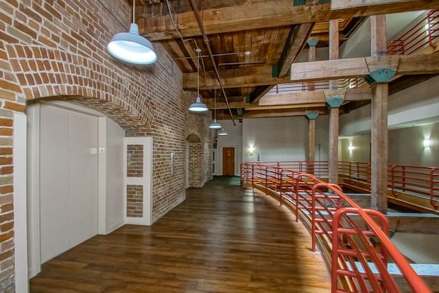 interior space featuring brick wall, wood-type flooring, and a high ceiling