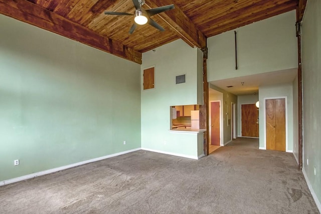 carpeted empty room featuring beamed ceiling, ceiling fan, high vaulted ceiling, and wooden ceiling