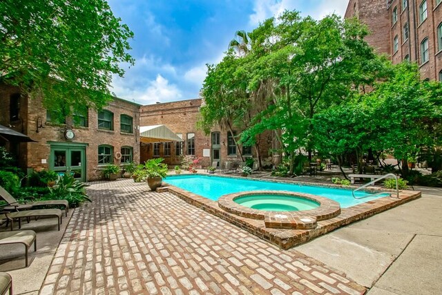 view of swimming pool featuring french doors, a hot tub, and a patio