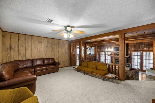 living room featuring ceiling fan, wood walls, french doors, and carpet flooring