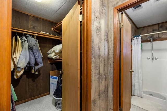 bathroom with wood walls and a shower with shower curtain