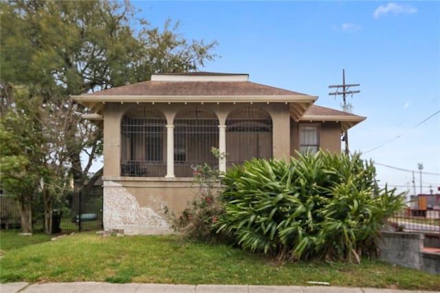 bungalow-style house featuring stucco siding, a front yard, and fence