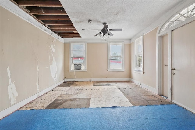 empty room with cooling unit, a textured ceiling, baseboards, and a ceiling fan