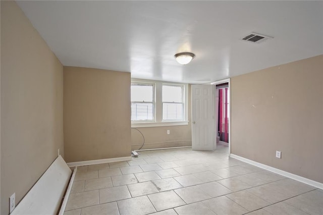 empty room with light tile patterned floors, baseboards, and visible vents