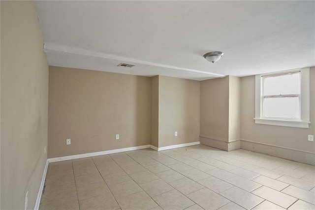 empty room with light tile patterned floors, baseboards, and visible vents