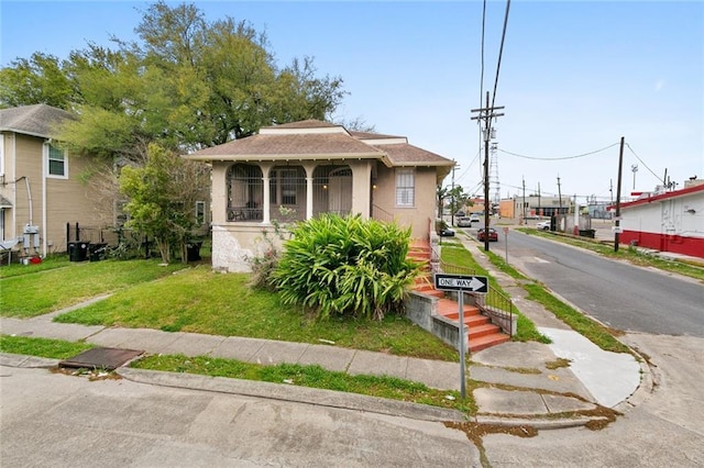 bungalow-style house with stucco siding and a front lawn