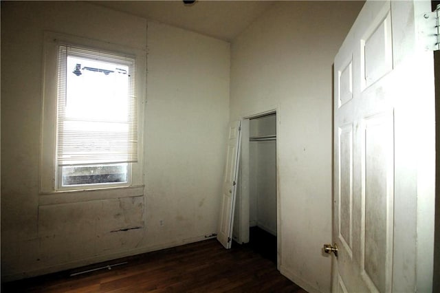 unfurnished bedroom featuring multiple windows, a closet, and dark wood-type flooring