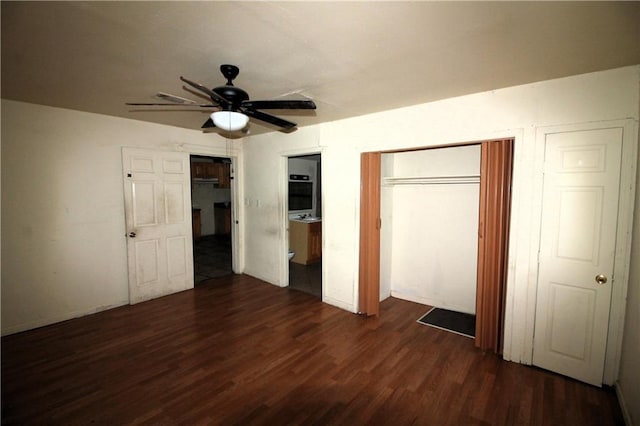 unfurnished bedroom featuring dark wood-type flooring, ensuite bathroom, and ceiling fan