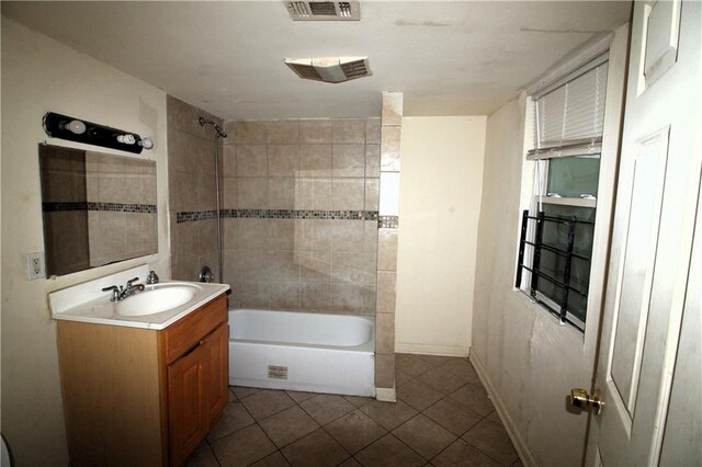 bathroom featuring tile floors, vanity, and tiled shower / bath combo