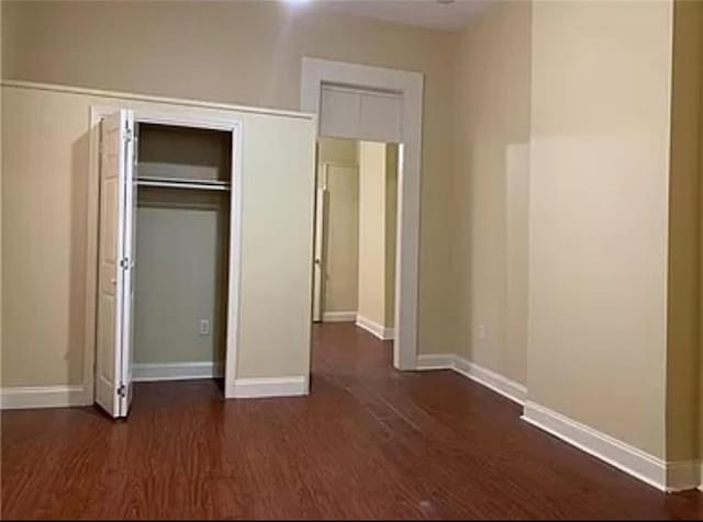 unfurnished bedroom with dark hardwood / wood-style floors and a closet