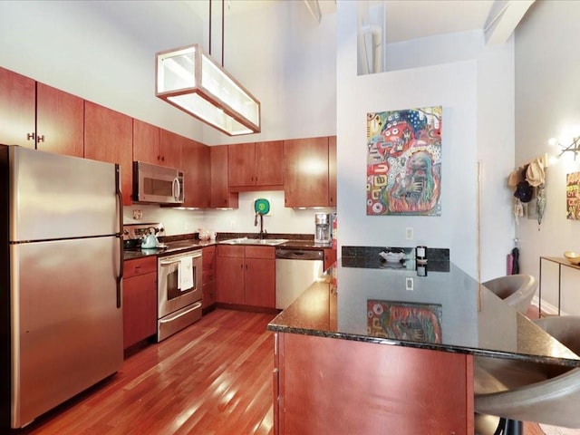 kitchen featuring sink, light hardwood / wood-style flooring, a kitchen bar, kitchen peninsula, and stainless steel appliances