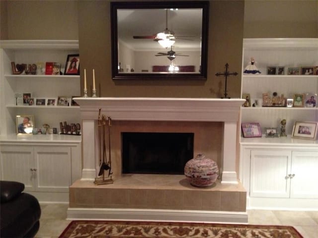 living area with ceiling fan, built in features, and a tiled fireplace