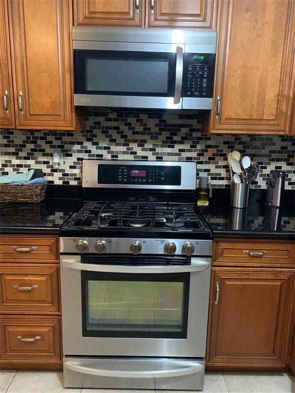 kitchen featuring stainless steel appliances, light tile patterned floors, and tasteful backsplash