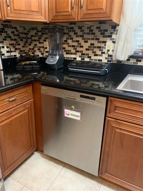 kitchen featuring dishwasher, dark stone counters, tasteful backsplash, and light tile patterned flooring