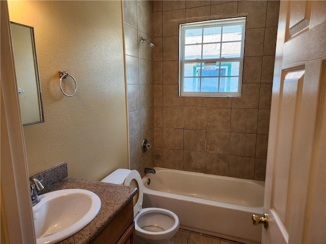 full bathroom with tiled shower / bath, toilet, tile floors, and large vanity