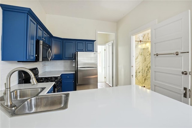 kitchen with blue cabinets, appliances with stainless steel finishes, sink, and decorative backsplash