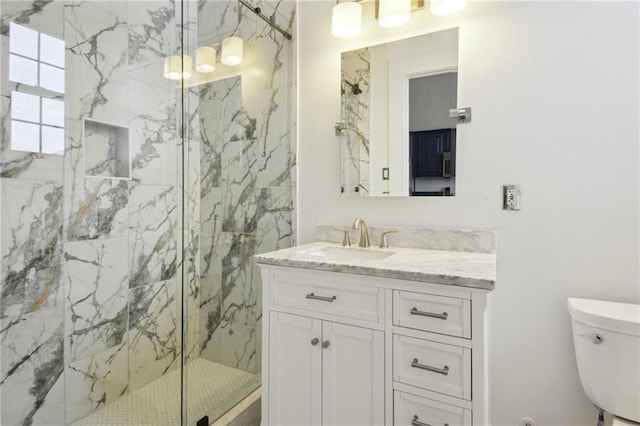 bathroom featuring a shower with door, vanity, and toilet