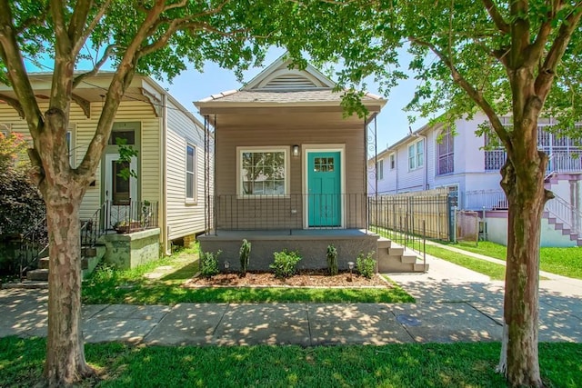 shotgun-style home featuring a porch and fence