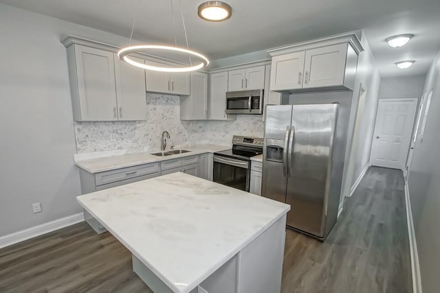 kitchen with a sink, light countertops, appliances with stainless steel finishes, hanging light fixtures, and gray cabinets